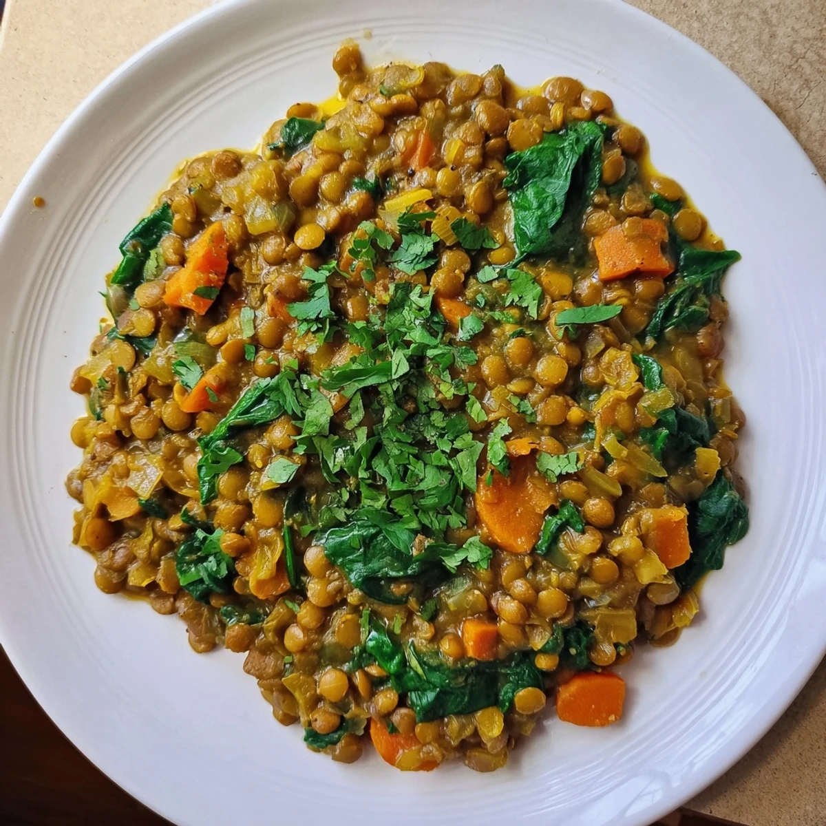 Steaming bowl of Lentil and Spinach Curry, garnished with cilantro, a warm, healthy vegan dinner.