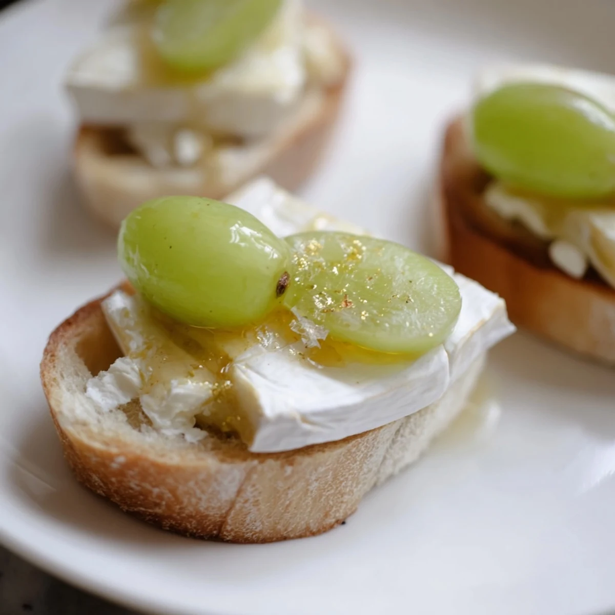 Sparkling Champagne Toast topped with golden grapes and creamy cheeses, perfect for a celebratory appetizer.