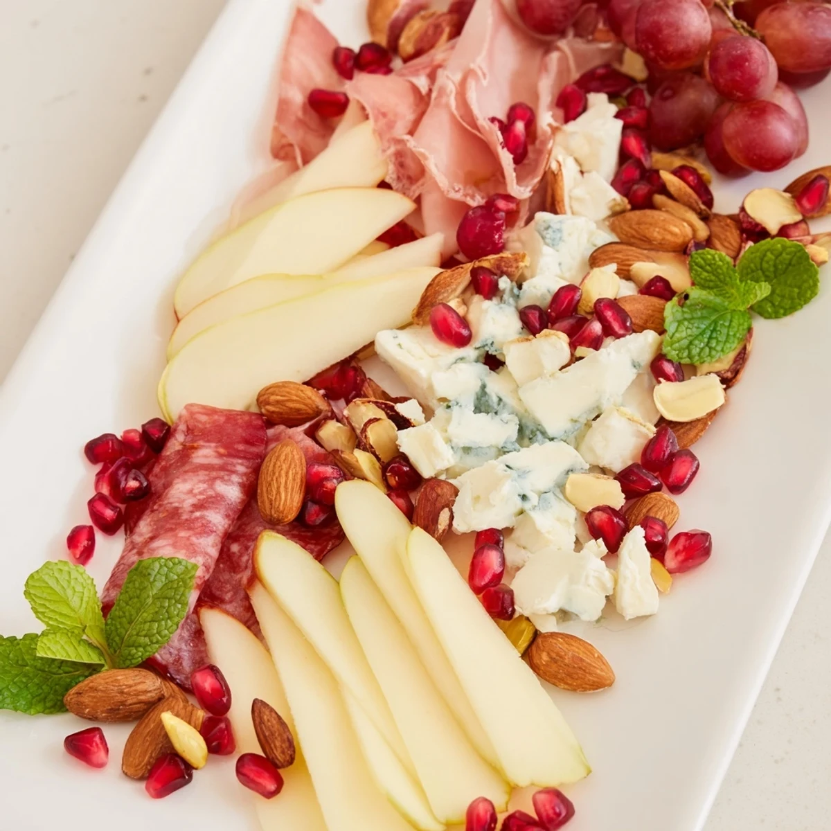 A gorgeous appetizer, the Pomegranate Jewel Cascade, boasts layered charcuterie, creamy cheeses, and glistening pomegranate arils.