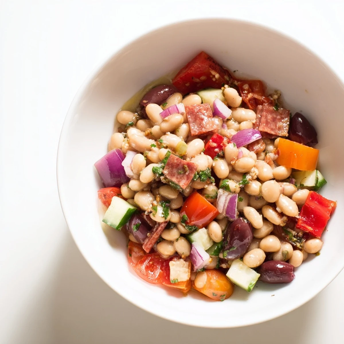 Mediterranean bean salad with salami, showcasing colorful vegetables and savory salami tossed in dressing.