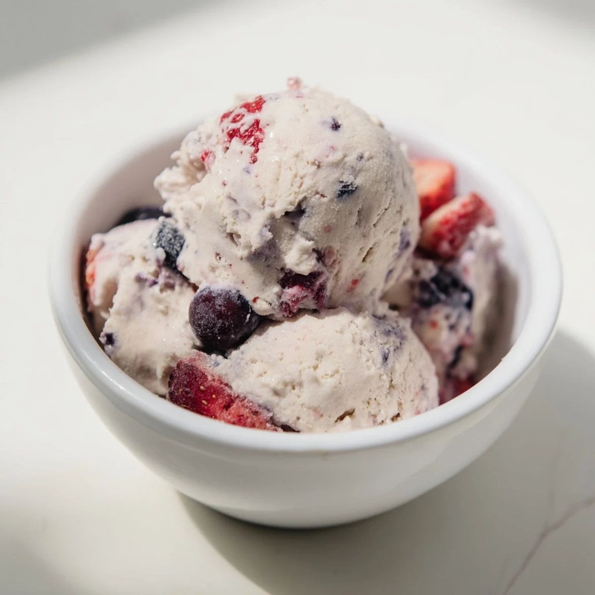 A scoop of Cottage Cheese Ice Cream, creamy and packed with frozen mixed berries, looks delicious.