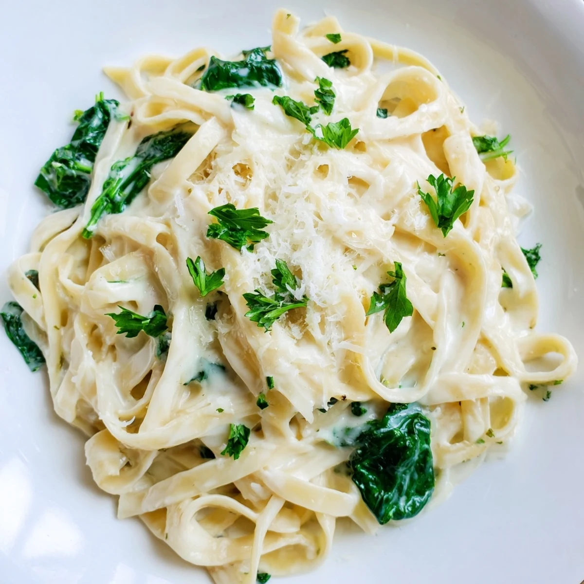 Garnish with parsley and Parmesan atop a steaming plate of Creamy Spinach Fettuccine Alfredo, ready to serve.