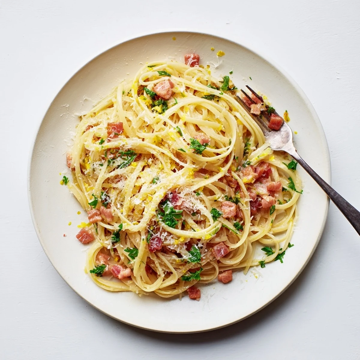 Steaming plate of Crispy Bacon Linguine garnished with fresh parsley, ready to serve with extra Parmesan on the side.