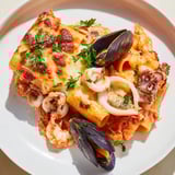 Steaming plate of seafood pasta bake with shrimp, mussels, and a rich, flavorful tomato sauce.