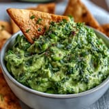 Creamy edamame guacamole with ripe avocado, cilantro, and lime, served with crispy baked pita chips for a healthy snack.  