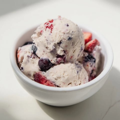 A scoop of Cottage Cheese Ice Cream, creamy and packed with frozen mixed berries, looks delicious.