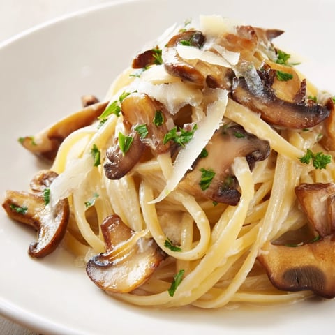 A close-up of creamy mushroom linguine, featuring golden sautéed mushrooms and fresh parsley on silky pasta.  