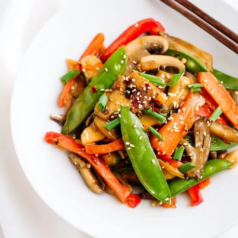 Bright orange carrots and green broccoli florets glistening with fresh ginger and savory soy sauce in a hot wok.