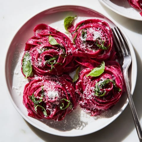 Fork-ready beet noodle pasta with earthy roasted flavors, served alongside a simple green salad for a vibrant meal.  