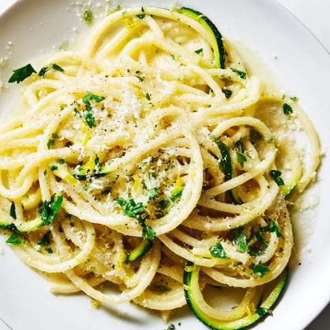 Steaming spiralized zucchini noodles and pasta coated in a bright lemon butter sauce with fresh parsley and grated Parmesan.