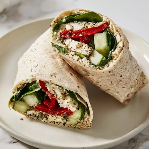 Close-up of a sliced Mediterranean Veggie Wrap revealing layers of feta, crisp veggies, and smoky peppers.  