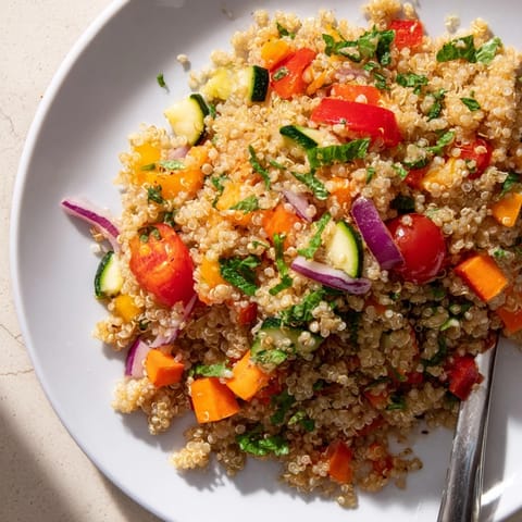Hearty Quinoa Vegetable Pilaf served in a rustic bowl, showcasing golden roasted carrots and red onion with a bright lemon wedge on the side.