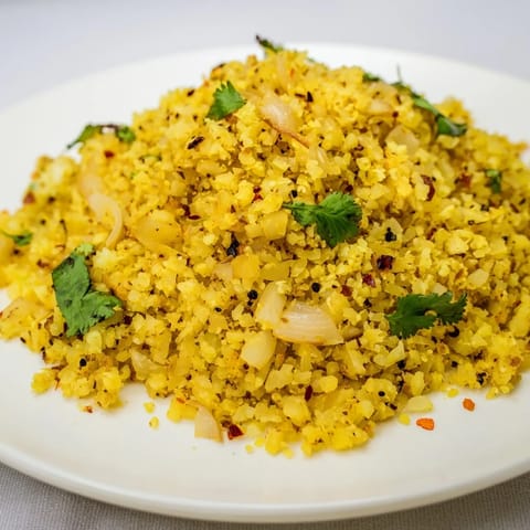 Fluffy, golden turmeric cauliflower rice cooked with onions, garlic, and fresh lemon, perfect alongside grilled chicken.