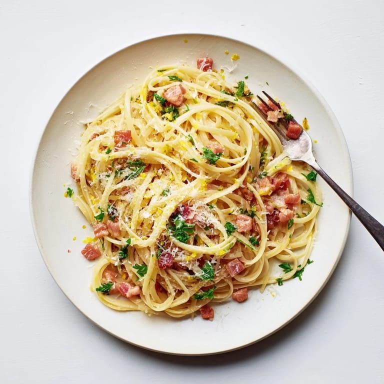 Steaming plate of Crispy Bacon Linguine garnished with fresh parsley, ready to serve with extra Parmesan on the side.