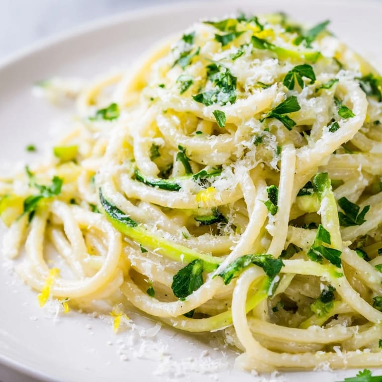 A close-up of Lemon Zucchini Pasta showcasing tender zoodles and golden pasta tossed in a vibrant, herb-speckled citrus sauce.