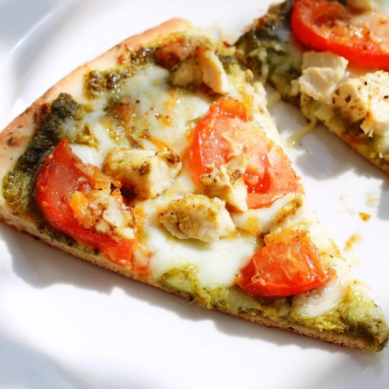 Slice of cheesy Chicken Pesto Pizza on a plate, with bubbling mozzarella and seasoned chicken, perfect for an easy family dinner.