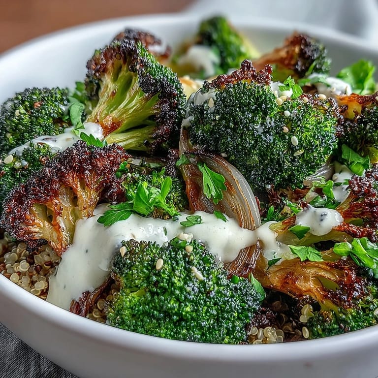 Spoon creamy tahini sauce over a vibrant roasted broccoli bowl with avocado slices and lemon wedges for a fresh finish.