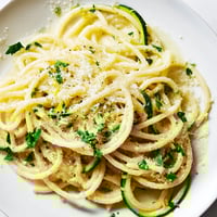 Steaming spiralized zucchini noodles and pasta coated in a bright lemon butter sauce with fresh parsley and grated Parmesan.